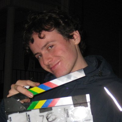 Enzo smirking and holding a film clapperboard